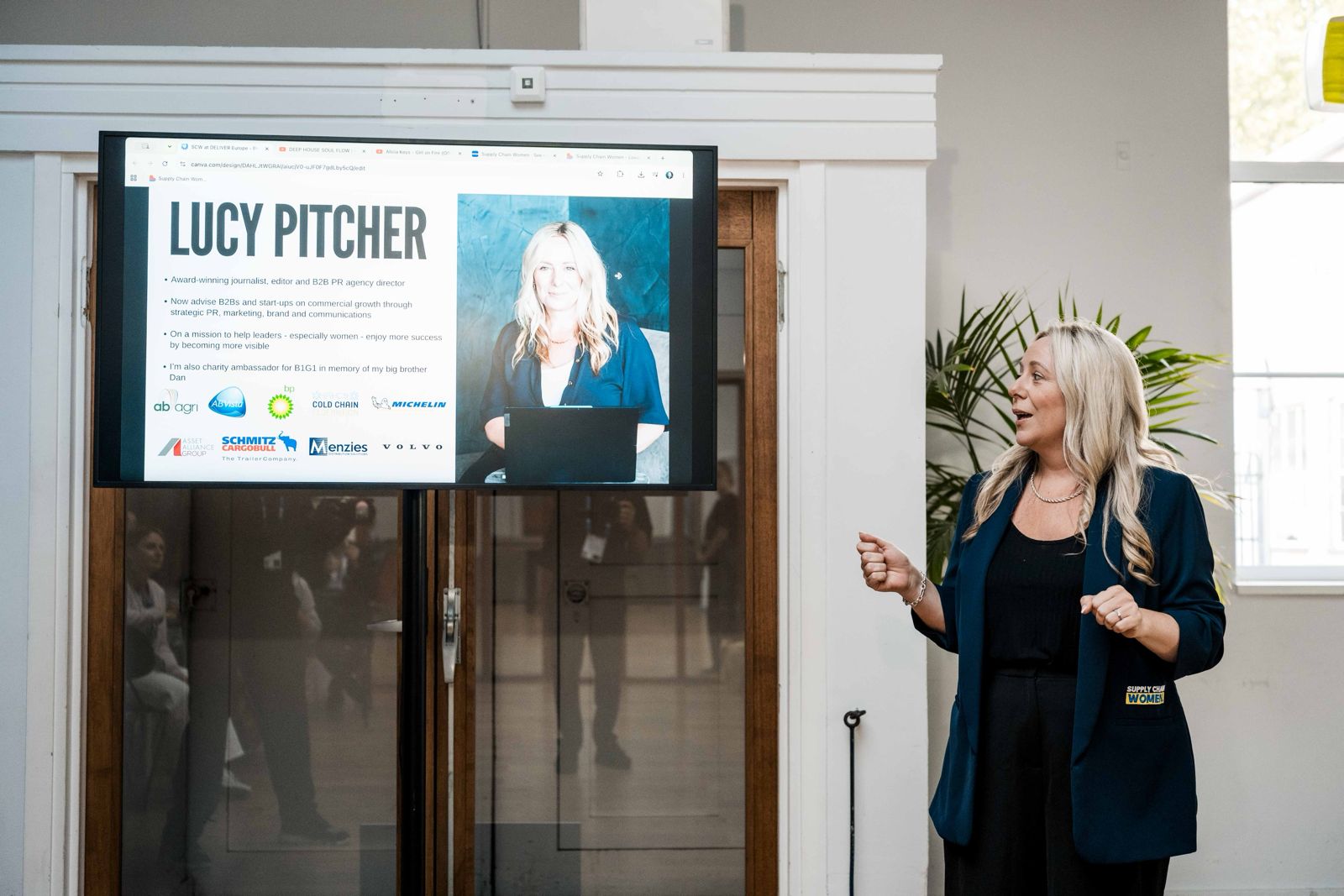 Lucy Pitcher presenting to an audience beside a screen